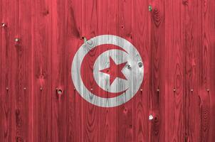 Tunisia flag depicted in bright paint colors on old wooden wall. Textured banner on rough background photo