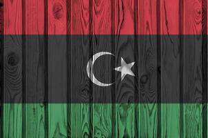 Libya flag depicted in bright paint colors on old wooden wall. Textured banner on rough background photo