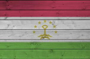 Tajikistan flag depicted in bright paint colors on old wooden wall. Textured banner on rough background photo