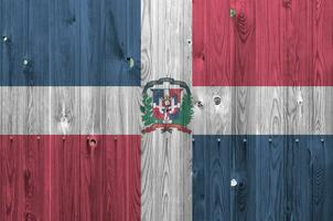 Dominican Republic flag depicted in bright paint colors on old wooden wall. Textured banner on rough background photo