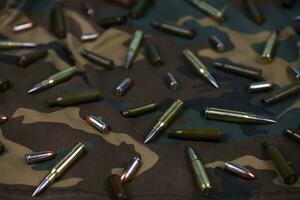 Many rifle bullets and cartridges on dark camouflage background photo