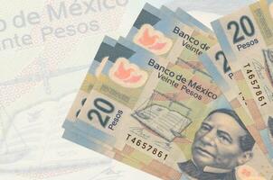 Los billetes de 20 pesos mexicanos se encuentran apilados sobre el fondo de un gran billete semitransparente. presentación abstracta de la moneda nacional foto