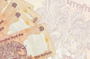 Los billetes de 10 rupias indias se encuentran apilados en el fondo de un gran billete semitransparente. fondo de negocios abstracto foto