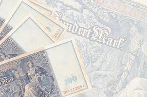 100 Reich marks bills lies in stack on background of big semi-transparent banknote. Abstract business background photo