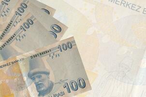 100 Turkish liras bills lies in stack on background of big semi-transparent banknote. Abstract business background photo