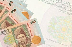 100 billetes de hryvnias ucranianos se encuentran apilados en el fondo de un gran billete semitransparente. fondo de negocios abstracto foto