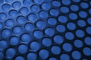 Black metal computer case panel mesh with holes on phantom classic blue color background. Abstract close up image photo