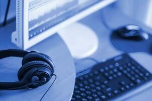 Big black headphones lie on the wooden desktop of the sound designer. phantom classic blue color tone photo