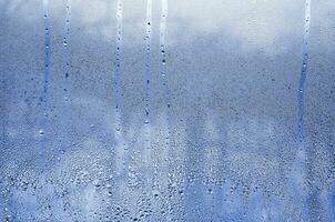 Texture of a drop of rain on a glass wet transparent background. Toned in phantom classic blue color tone photo