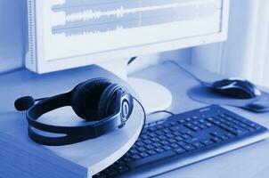 Big black headphones lie on the wooden desktop of the sound designer. phantom classic blue color tone photo