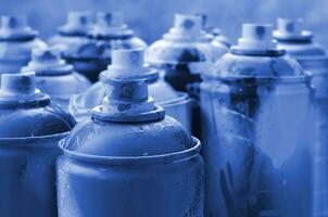 A lot of dirty and used aerosol cans of phantom classic blue colorpaint. Macro photograph with shallow depth of field. Selective focus on the spray nozzle photo