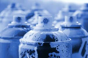 A lot of dirty and used aerosol cans of phantom classic blue colorpaint. Macro photograph with shallow depth of field. Selective focus on the spray nozzle photo