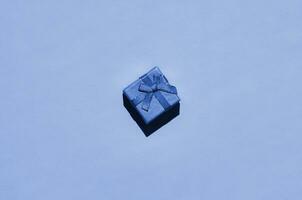 Small gift box lie on texture background of fashion trendy phantom classic blue color paper in minimal concept photo