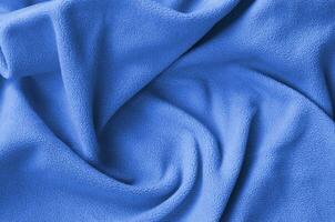 The blanket of furry fleece fabric. A background of soft plush fleece material with a lot of relief folds. phantom classic blue color photo