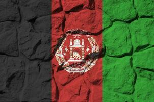 Afghanistan flag depicted in paint colors on old stone wall closeup. Textured banner on rock wall background photo