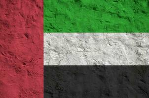 United Arab Emirates flag depicted in bright paint colors on old relief plastering wall. Textured banner on rough background photo