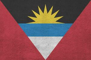 Antigua and Barbuda flag depicted in bright paint colors on old relief plastering wall. Textured banner on rough background photo