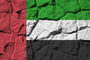 unido árabe emiratos bandera representado en pintar colores en antiguo Roca pared de cerca. texturizado bandera en rock pared antecedentes foto