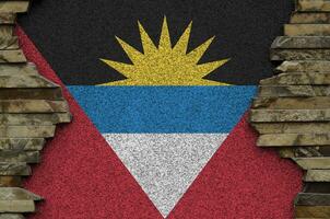 Antigua and Barbuda flag depicted in paint colors on old stone wall closeup. Textured banner on rock wall background photo