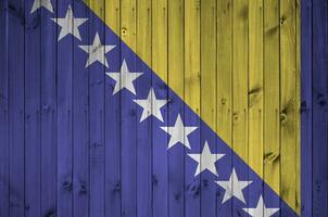 bosnia y herzegovina bandera representado en brillante pintar colores en antiguo de madera pared. texturizado bandera en áspero antecedentes foto