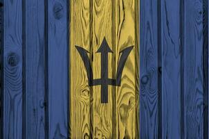 Barbados flag depicted in bright paint colors on old wooden wall. Textured banner on rough background photo