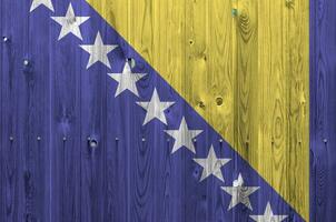 bosnia y herzegovina bandera representado en brillante pintar colores en antiguo de madera pared. texturizado bandera en áspero antecedentes foto