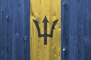 Barbados flag depicted in bright paint colors on old wooden wall. Textured banner on rough background photo