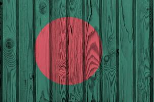 Bangladesh bandera representado en brillante pintar colores en antiguo de madera pared. texturizado bandera en áspero antecedentes foto