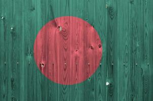 Bangladesh bandera representado en brillante pintar colores en antiguo de madera pared. texturizado bandera en áspero antecedentes foto