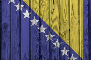 bosnia y herzegovina bandera representado en brillante pintar colores en antiguo de madera pared. texturizado bandera en áspero antecedentes foto