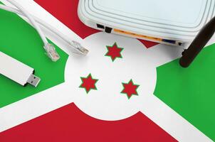 Burundi flag depicted on table with internet rj45 cable, wireless usb wifi adapter and router. Internet connection concept photo