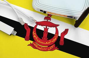 Brunei Darussalam flag depicted on table with internet rj45 cable, wireless usb wifi adapter and router. Internet connection concept photo