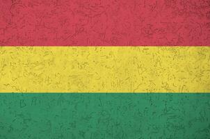 Bolivia flag depicted in bright paint colors on old relief plastering wall. Textured banner on rough background photo