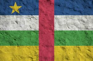 Central African Republic flag depicted in bright paint colors on old relief plastering wall. Textured banner on rough background photo