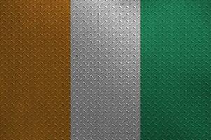 Ivory Coast flag depicted in paint colors on old brushed metal plate or wall closeup. Textured banner on rough background photo