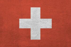 bandera suiza representada en colores de pintura brillante en la antigua pared de yeso en relieve. banner texturizado sobre fondo áspero foto