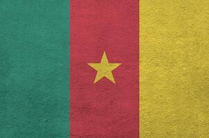 Cameroon flag depicted in bright paint colors on old relief plastering wall. Textured banner on rough background photo