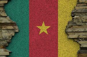 Cameroon flag depicted in paint colors on old stone wall closeup. Textured banner on rock wall background photo