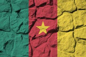 Cameroon flag depicted in paint colors on old stone wall closeup. Textured banner on rock wall background photo