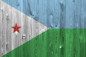 Djibouti flag depicted in bright paint colors on old wooden wall. Textured banner on rough background photo