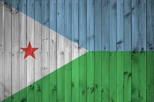 Djibouti flag depicted in bright paint colors on old wooden wall. Textured banner on rough background photo