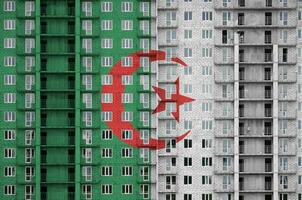 Algeria flag depicted in paint colors on multi-storey residental building under construction. Textured banner on brick wall background photo