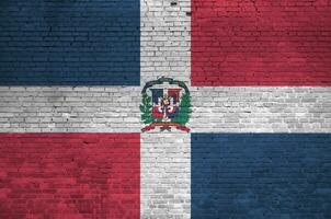 Dominican Republic flag depicted in paint colors on old brick wall. Textured banner on big brick wall masonry background photo