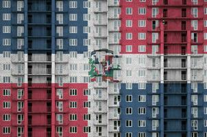 dominicano república bandera representado en pintar colores en de muchos pisos residencial edificio debajo construcción. texturizado bandera en ladrillo pared antecedentes foto