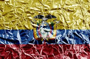 Ecuador flag depicted in paint colors on shiny crumpled aluminium foil closeup. Textured banner on rough background photo