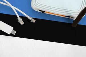 Estonia flag depicted on table with internet rj45 cable, wireless usb wifi adapter and router. Internet connection concept photo