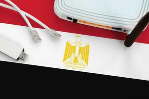 Egypt flag depicted on table with internet rj45 cable, wireless usb wifi adapter and router. Internet connection concept photo