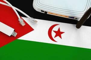 Western Sahara flag depicted on table with internet rj45 cable, wireless usb wifi adapter and router. Internet connection concept photo