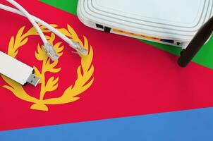 Eritrea flag depicted on table with internet rj45 cable, wireless usb wifi adapter and router. Internet connection concept photo