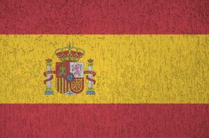 Spain flag depicted in bright paint colors on old relief plastering wall. Textured banner on rough background photo